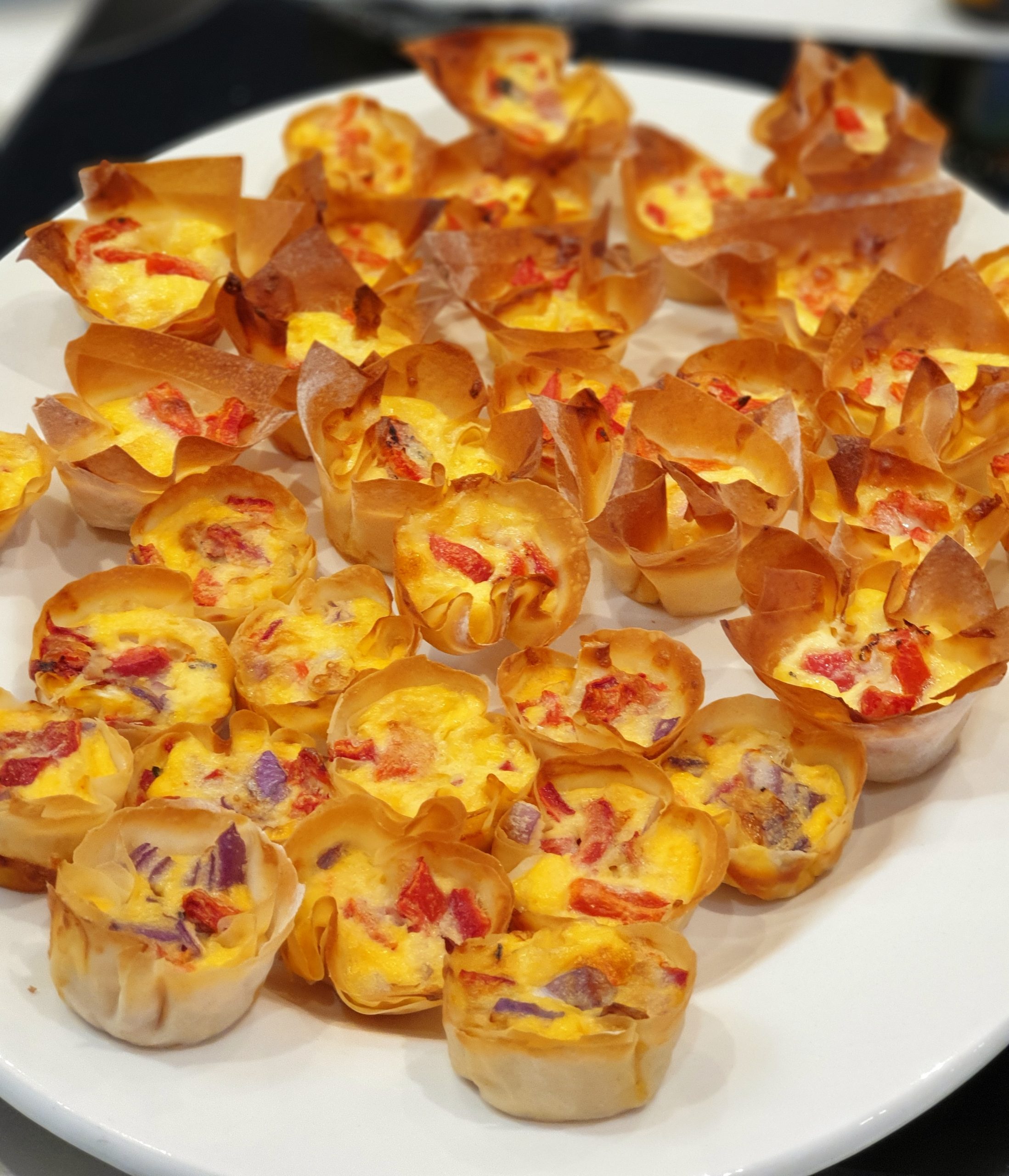 Plate of miniature filo red pepper and gruyere tartlets